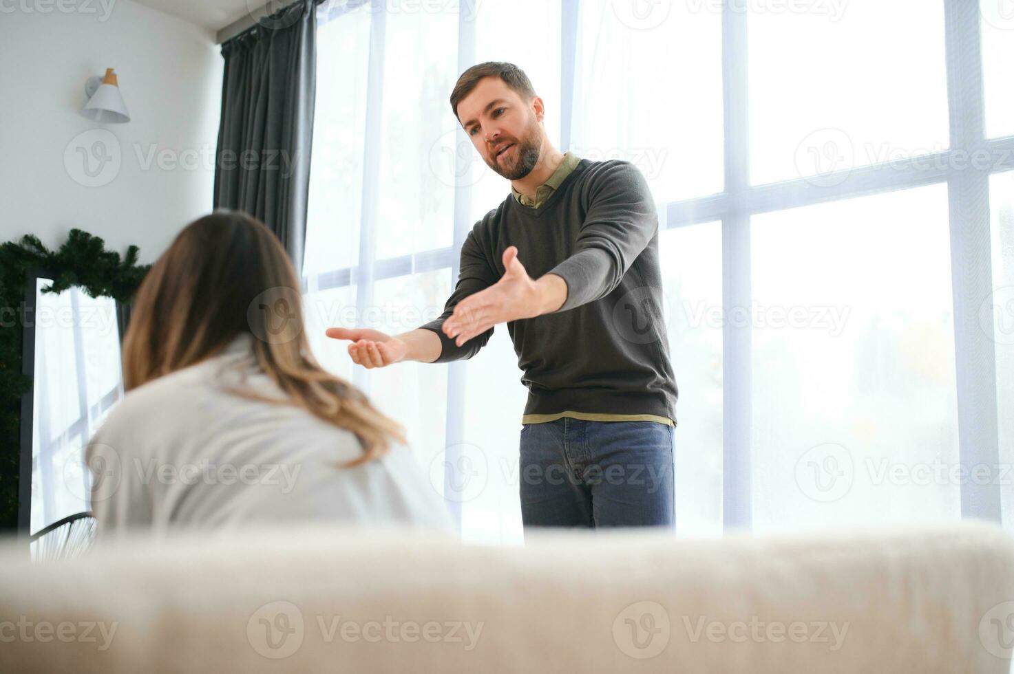 Emotional man gesturing and shouting at his wife, young couple having quarrel at home. Domestic abuse concept photo