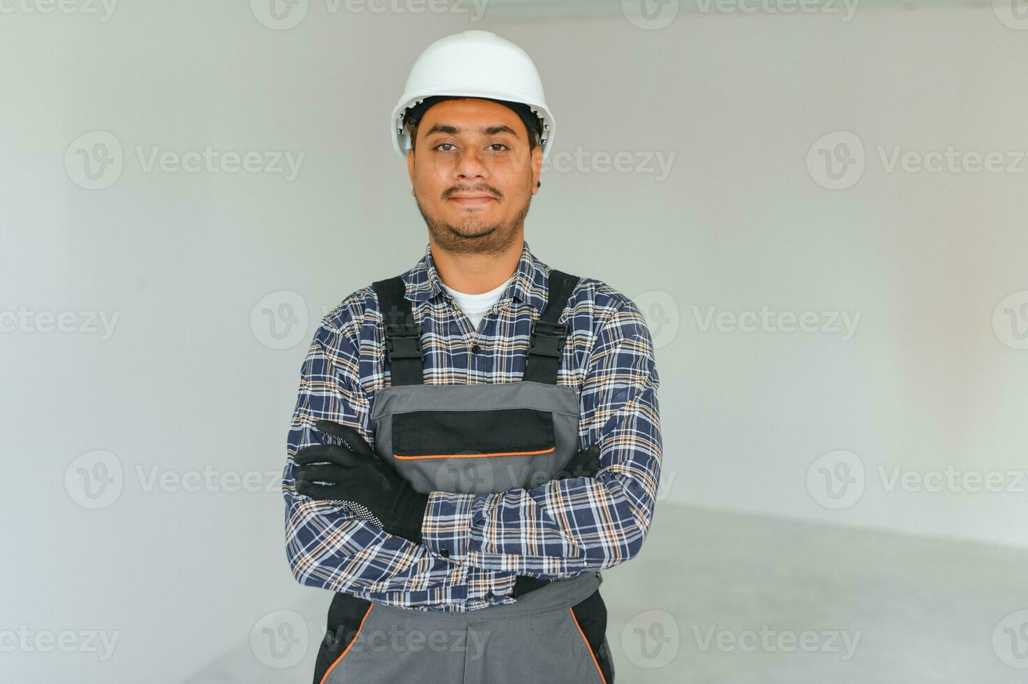 profesión, construcción y edificio - contento sonriente indio trabajador o constructor en casco terminado gris antecedentes. foto