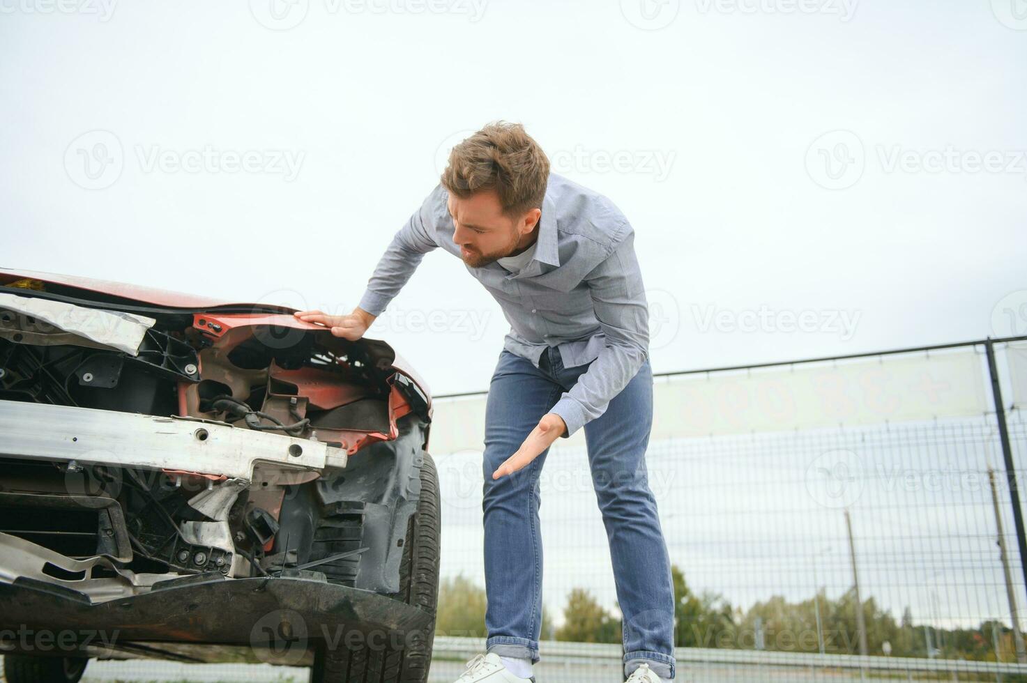 joven hombre conductor en coche accidente cerca roto coche en el la carretera después un coche accidente foto