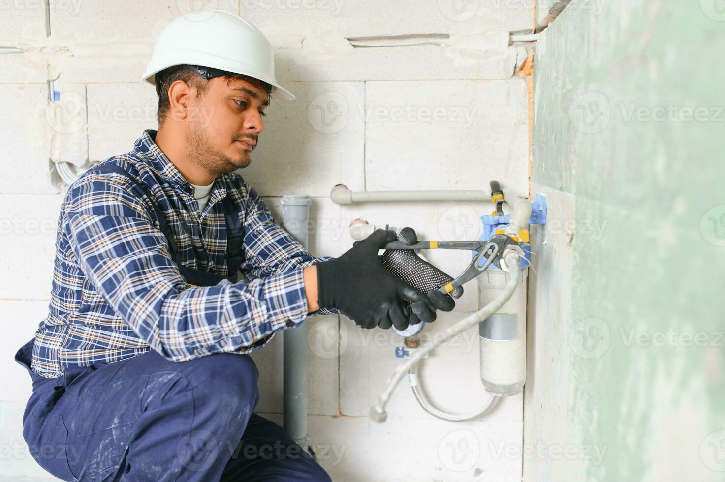 Indian plumber installing water equipment - meter, filter and pressure reducer photo