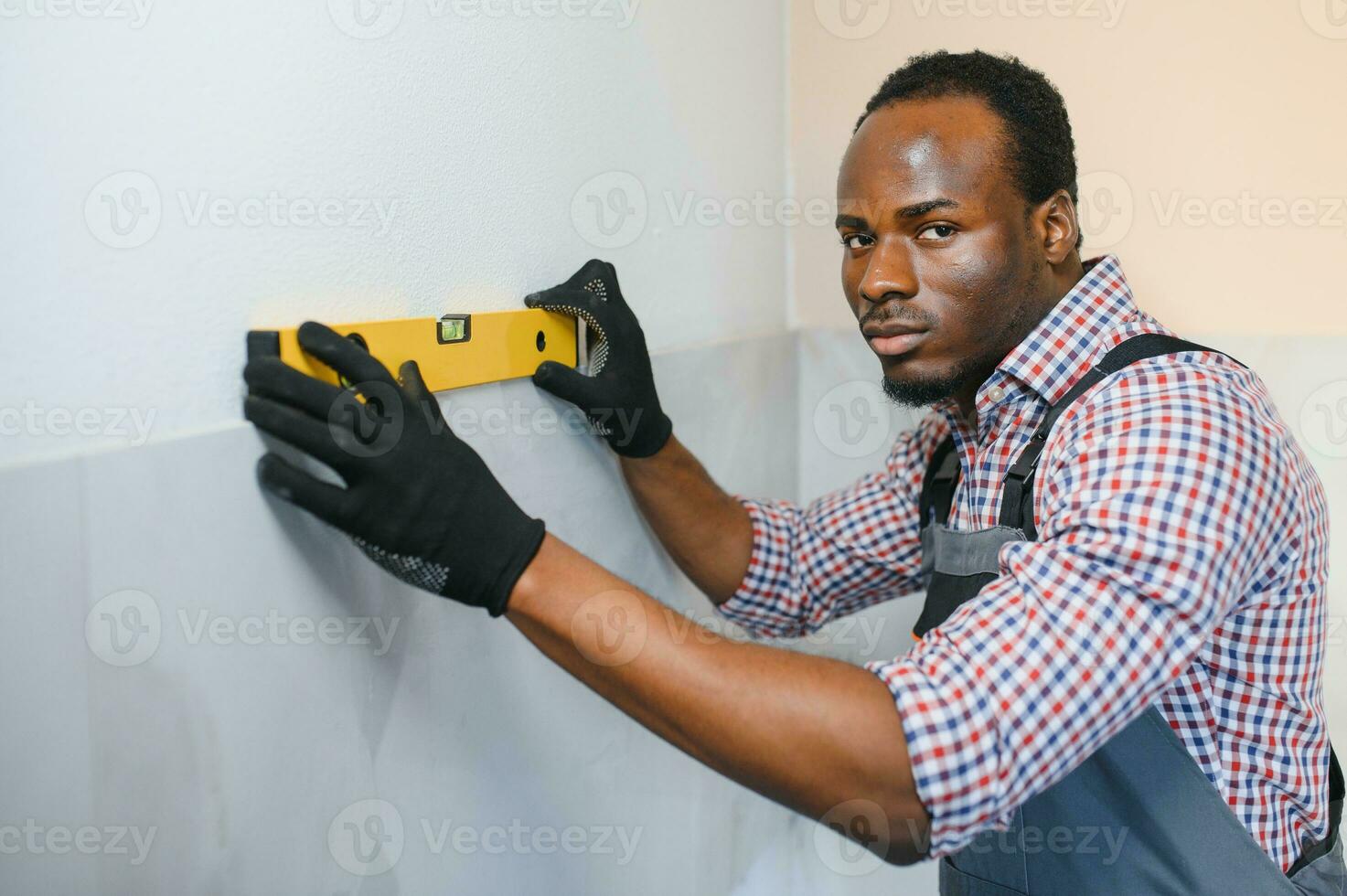 African American Worker installing wall tile with vacuum holder indoors photo