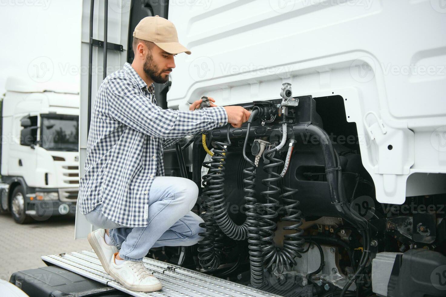 View of a driver connecting the power cables to trailer of a commercial truck photo