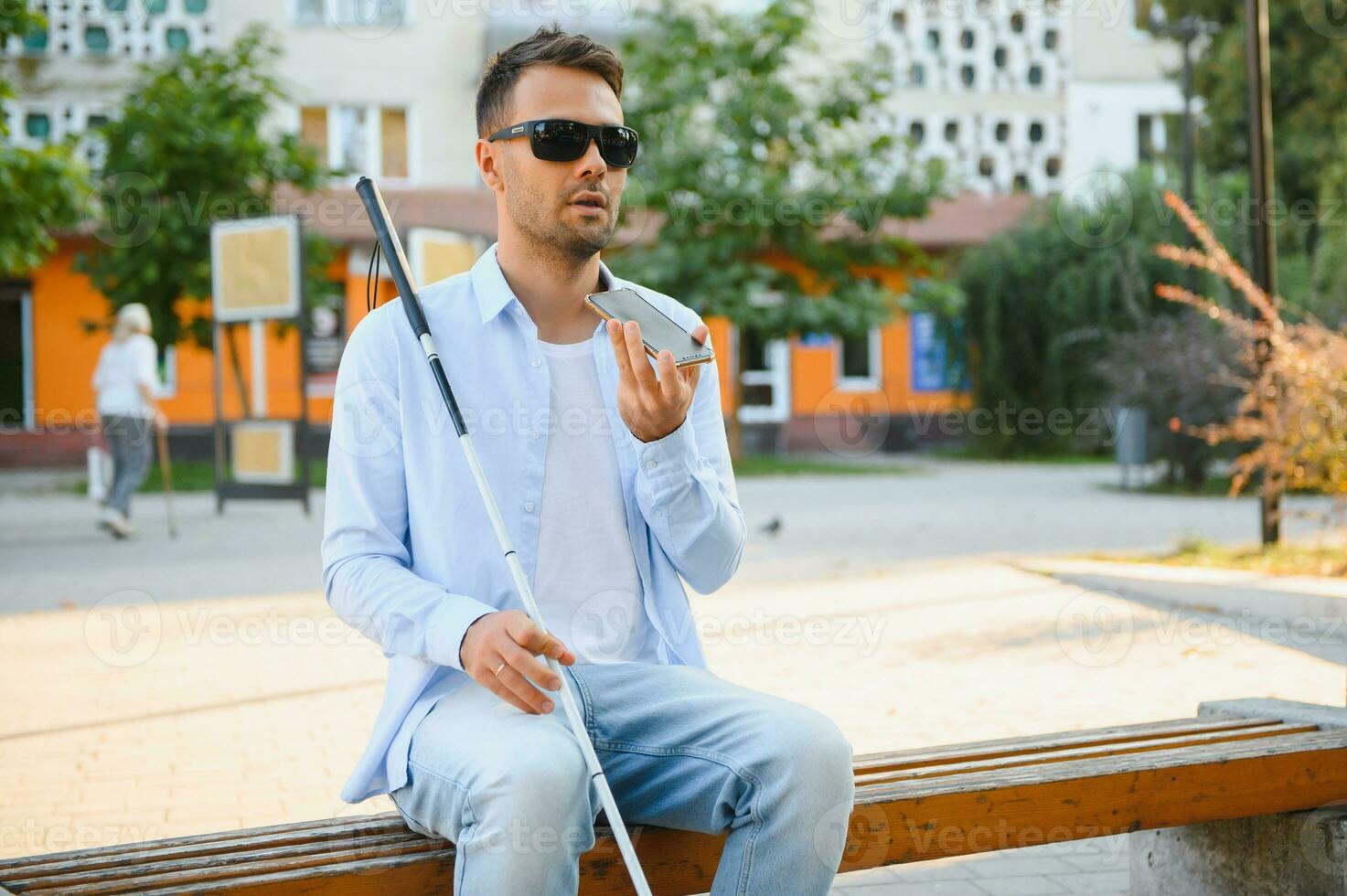 Young blinded man using phone and sending voice message photo