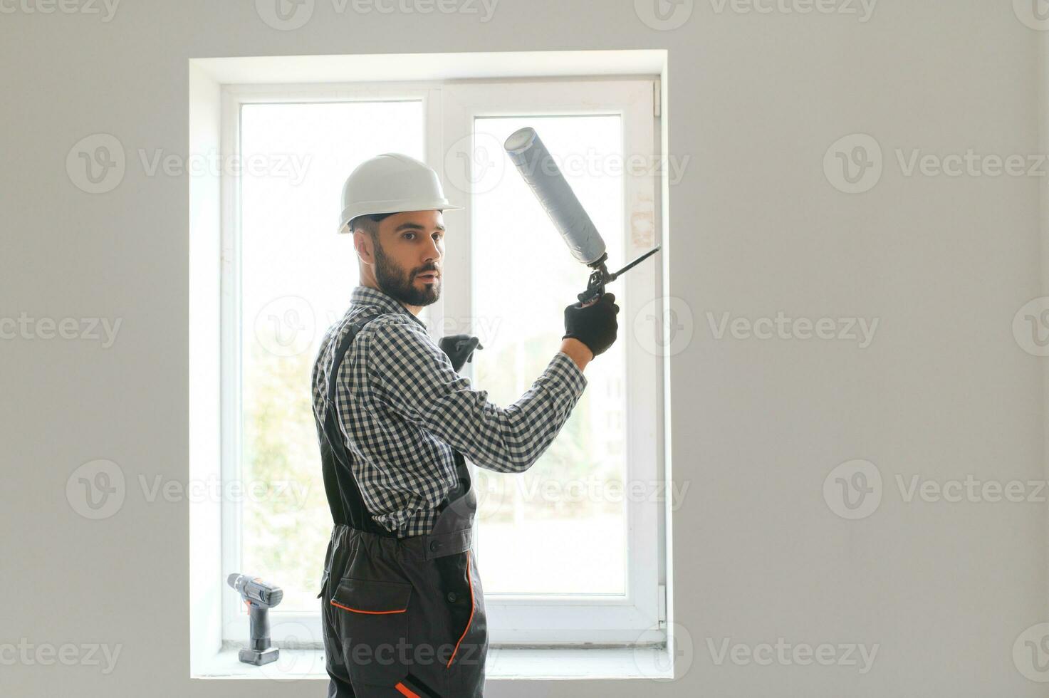 Side View Of A Young Male Worker Applying Glue With Silicone Gun photo