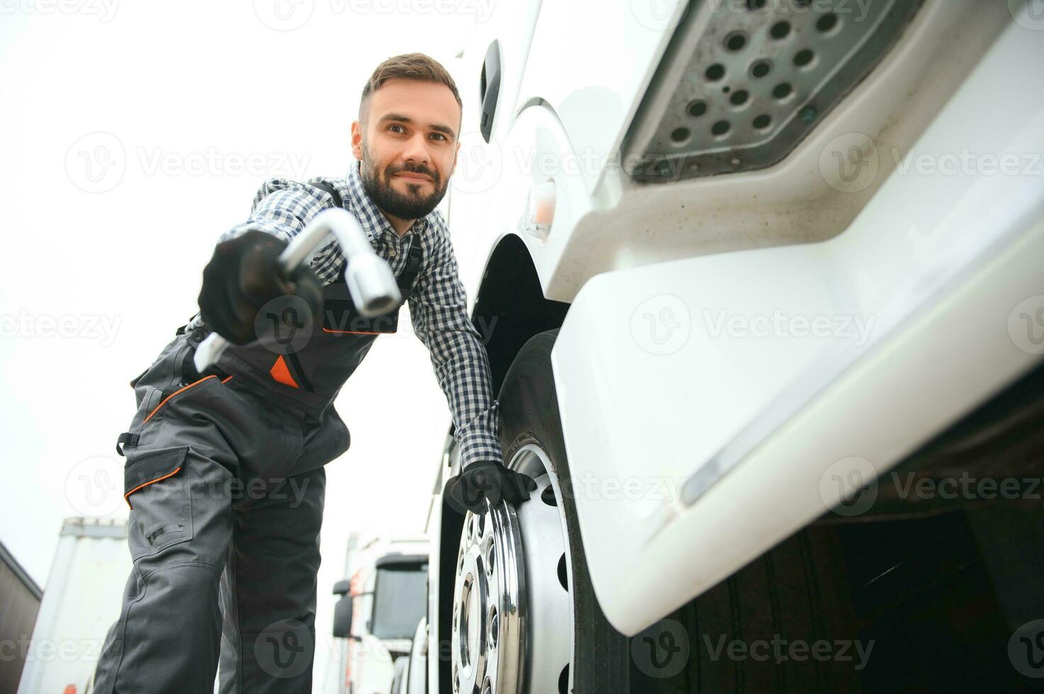 Working with damaged tire. Young truck driver is with his vehicle at daytime photo