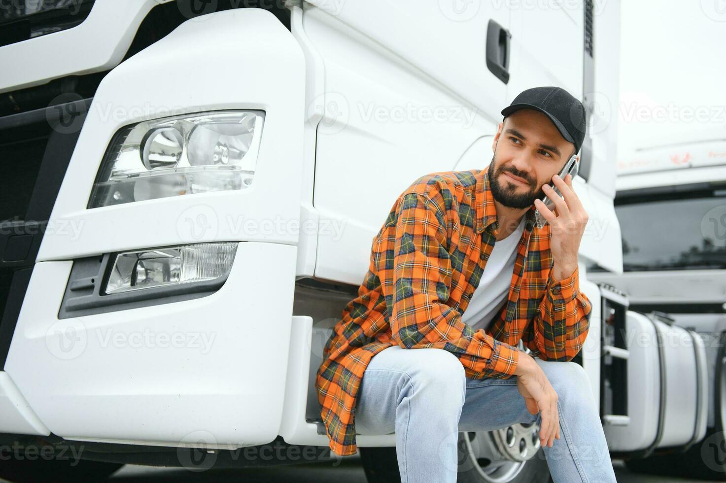 Man trucker talking on the phone by his white truck photo