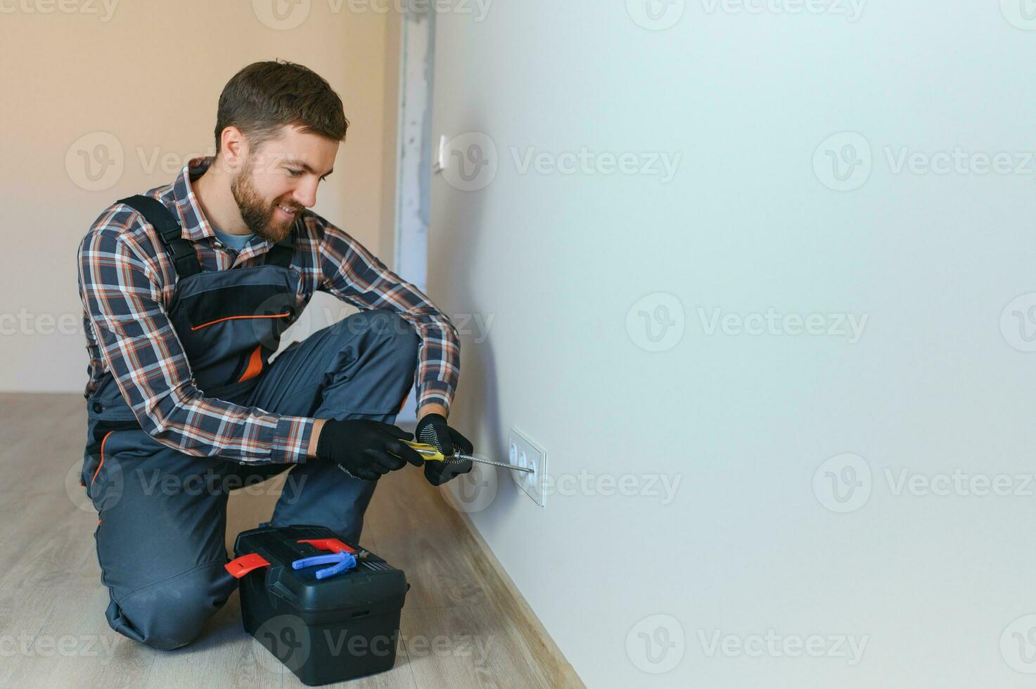 Electrician with screwdriver repairing power socket in room photo