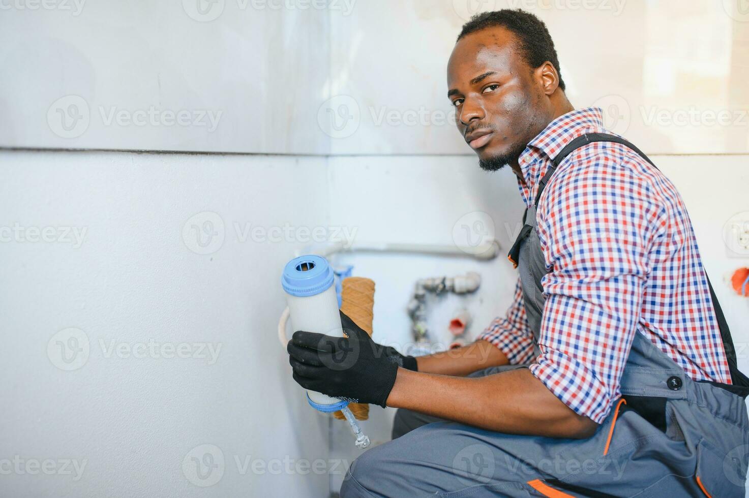 African American Plumber installs or change water filter. Replacement