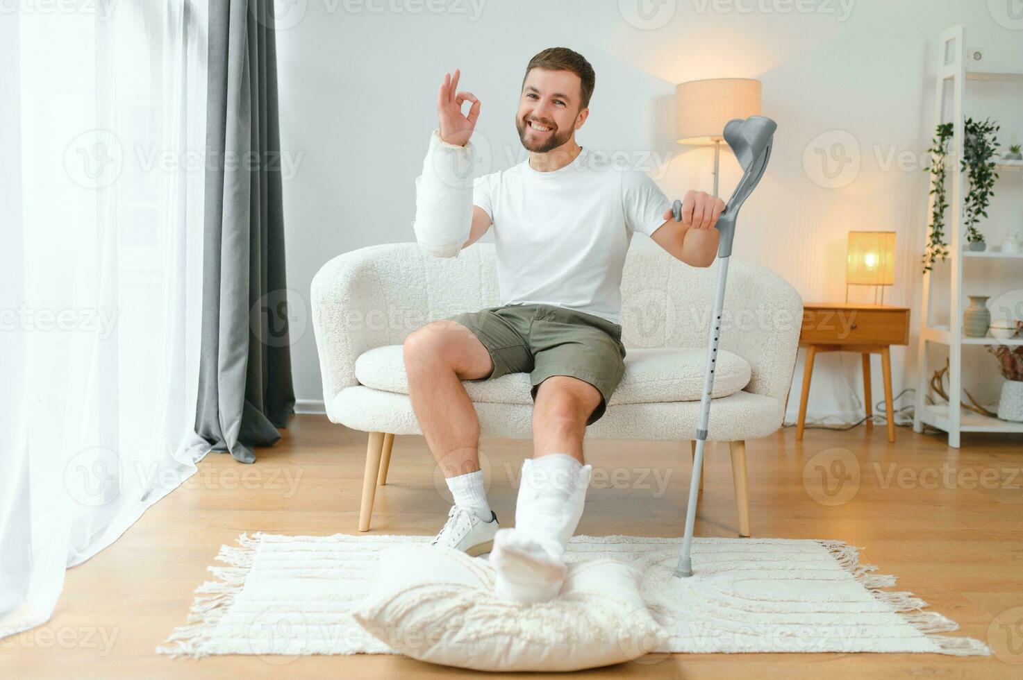 man recovery from accident fracture broken bone injury with leg splints in cast neck splints collar arm splints sling support arm in living room. Social security and health insurance concept photo