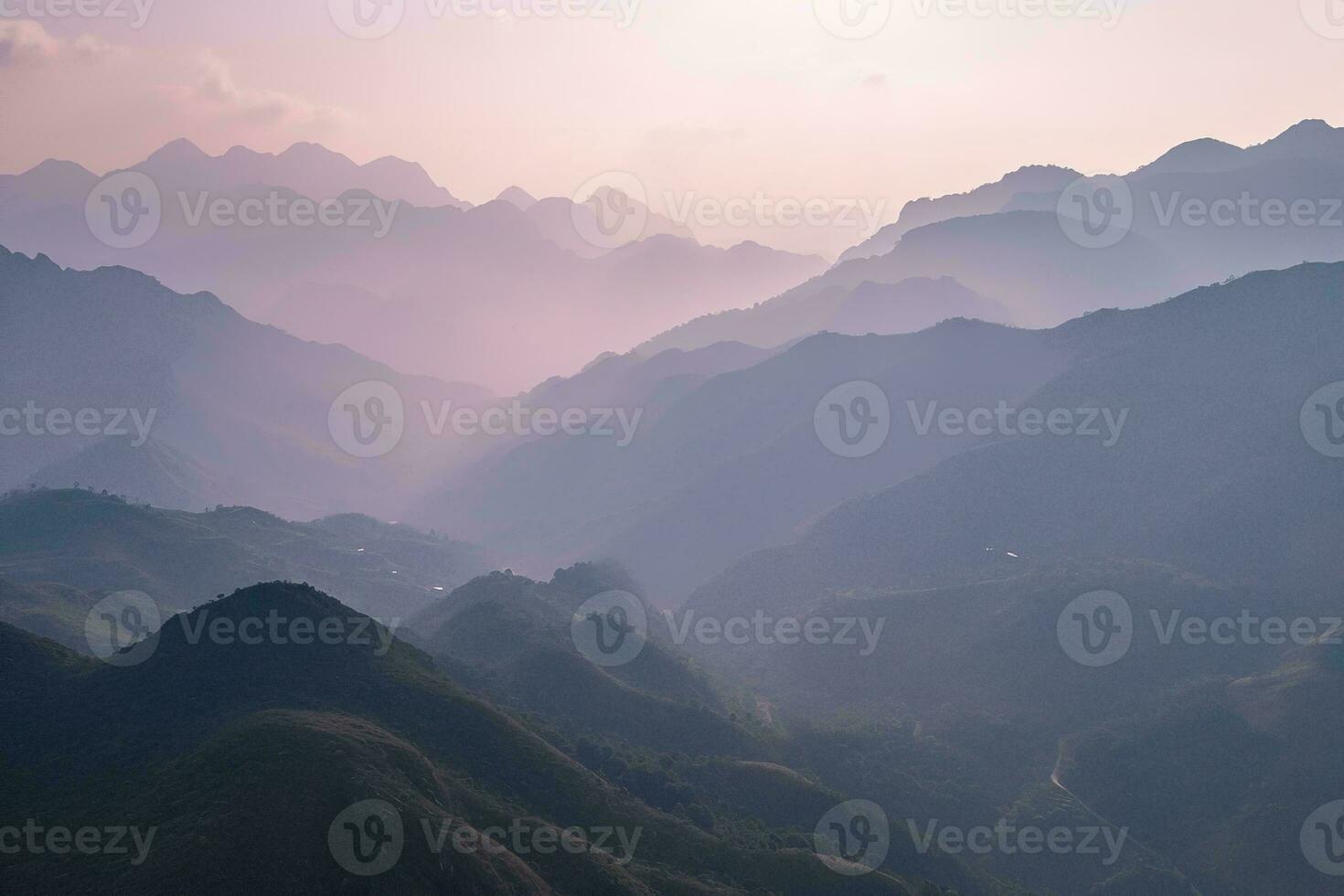 AI generated A tranquil scene of layered mountains veiled in mist, illuminated by the gentle hues of a setting sun, evoking peace. photo