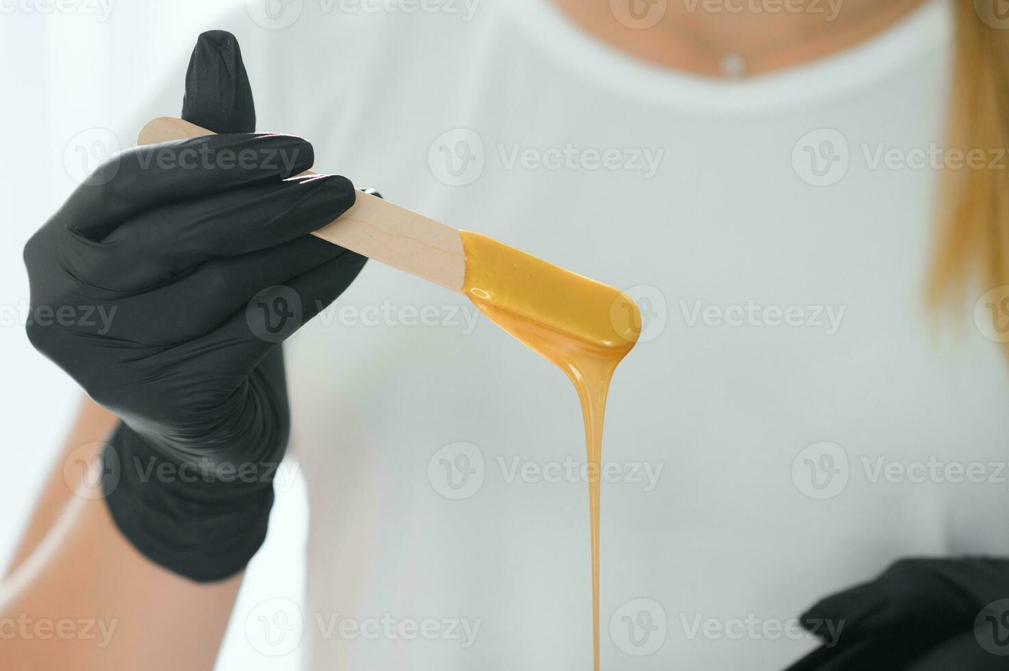 Female cosmetologist holding stick with wax for depilation or sugaring photo