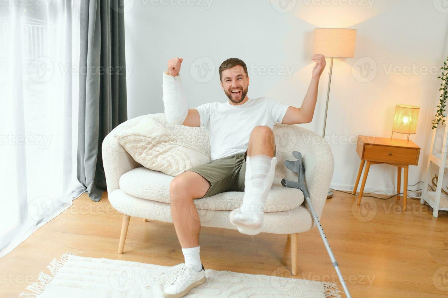 Man with multiple physical limb and body injuries recovers after accident. Happy guy having fun at home photo