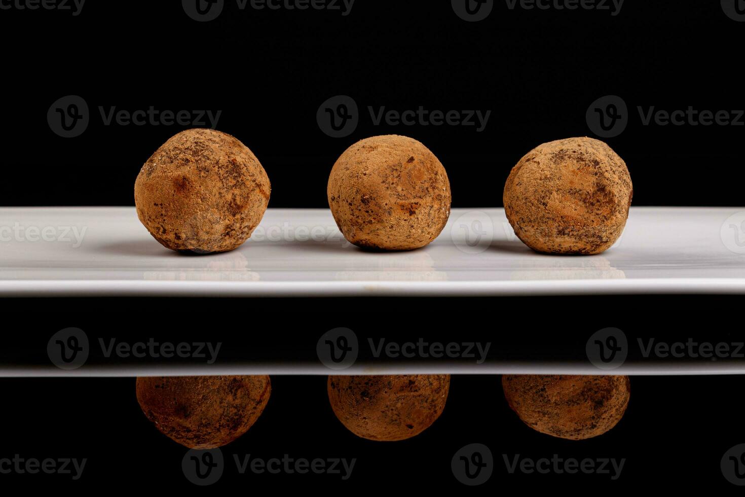 Beautiful candy truffle on a white plate on a black background photo