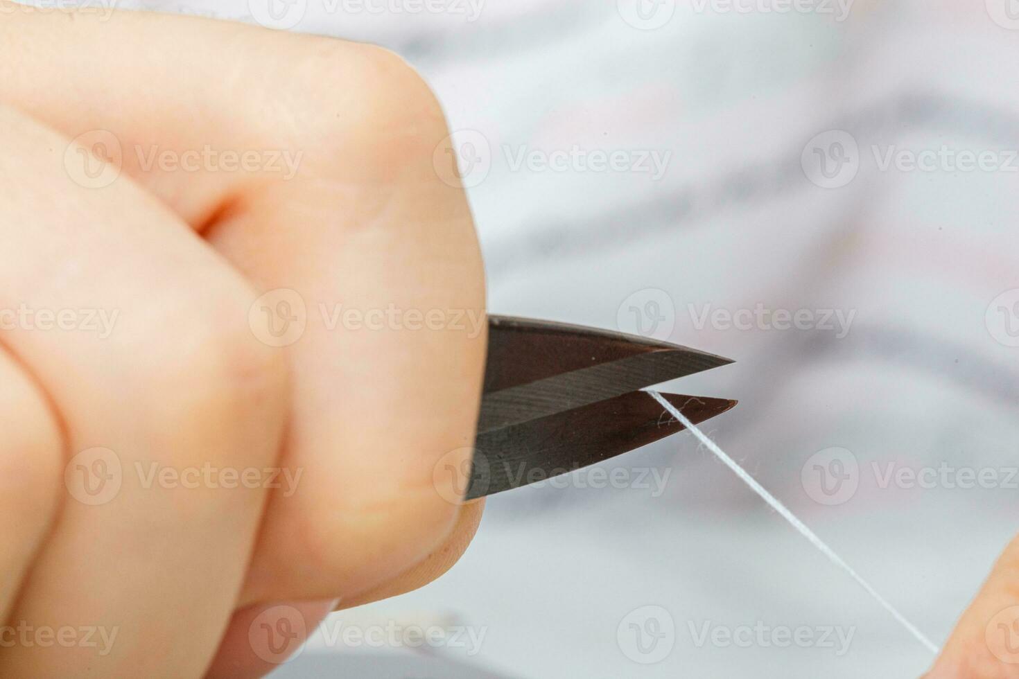 Female hands of a master tailor cuts a thread with scissors photo