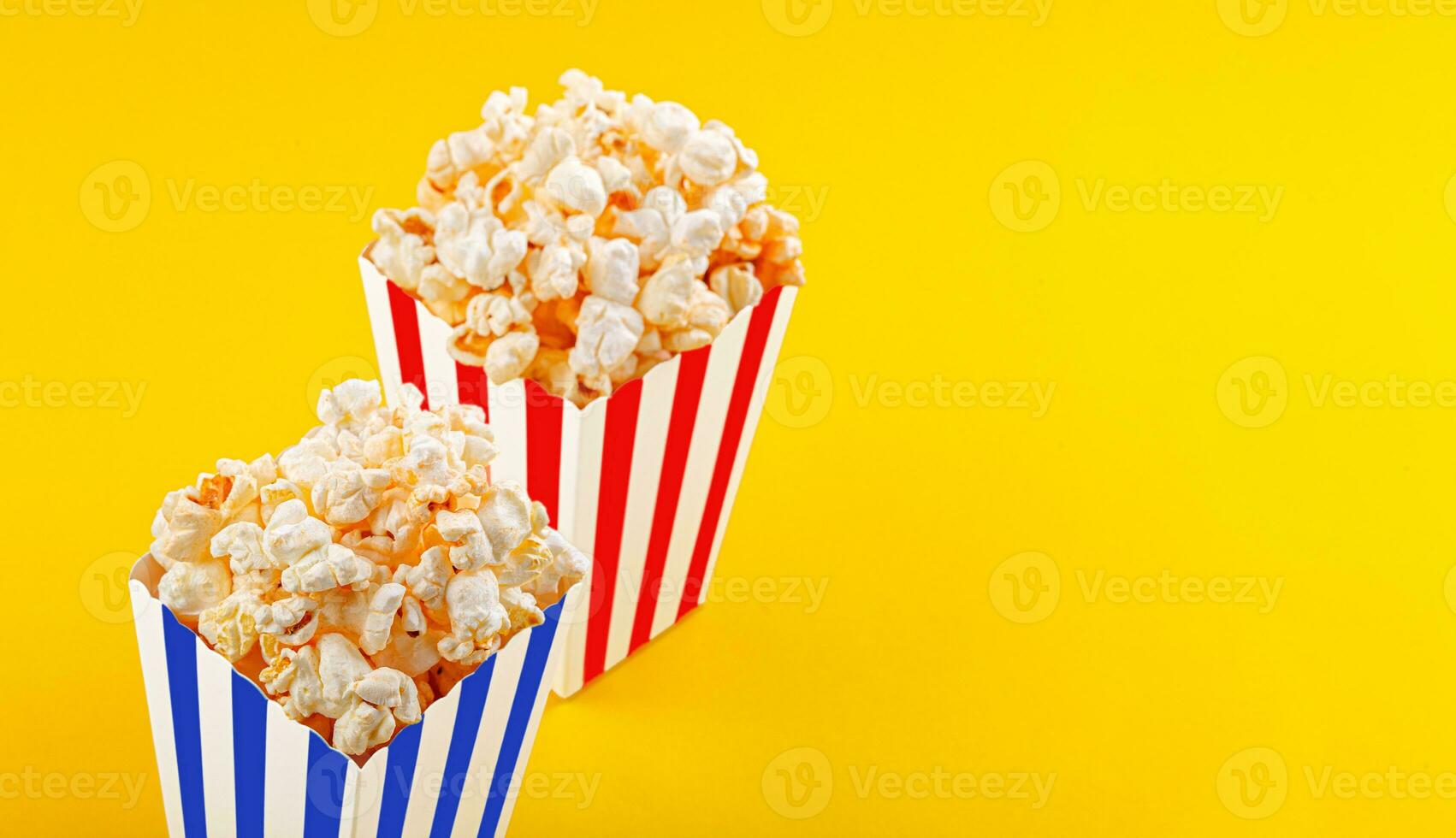 Glass with popcorn on a yellow background photo