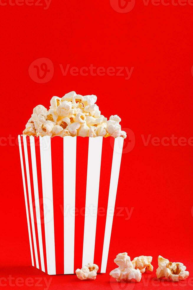 Glass with popcorn on a red background photo