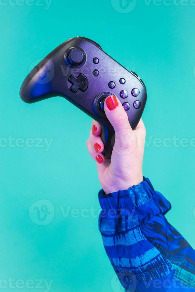 Female hand holding a video game controller gamepad isolated on a blue background studio. photo