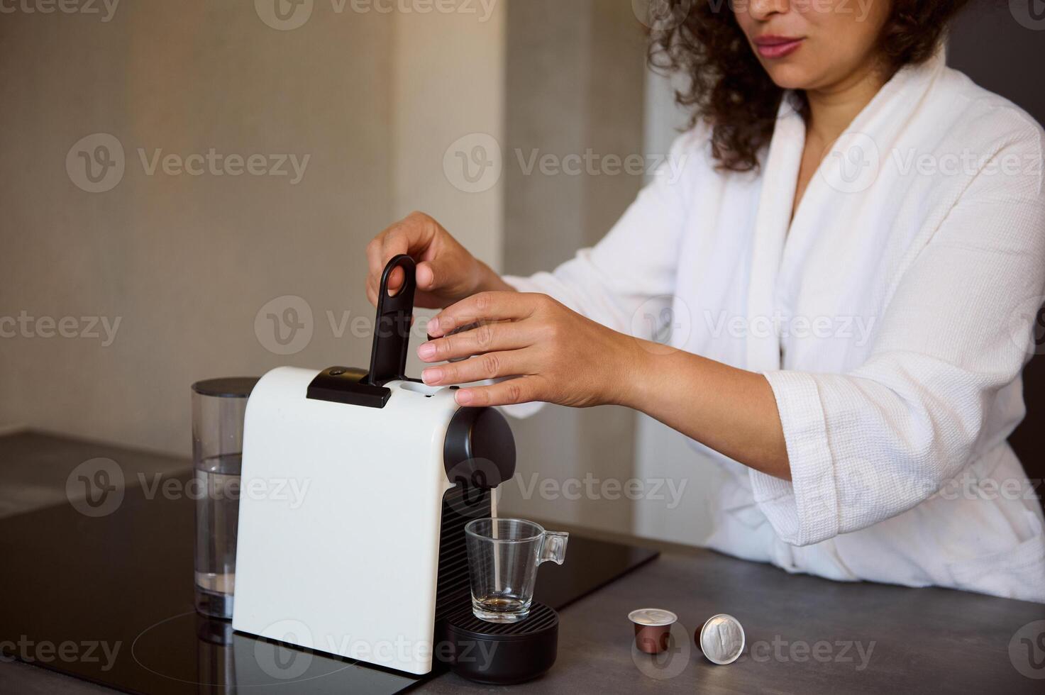 Details on hands of young woman inserting a capsule with grinded coffee inside a coffee machine for home use photo