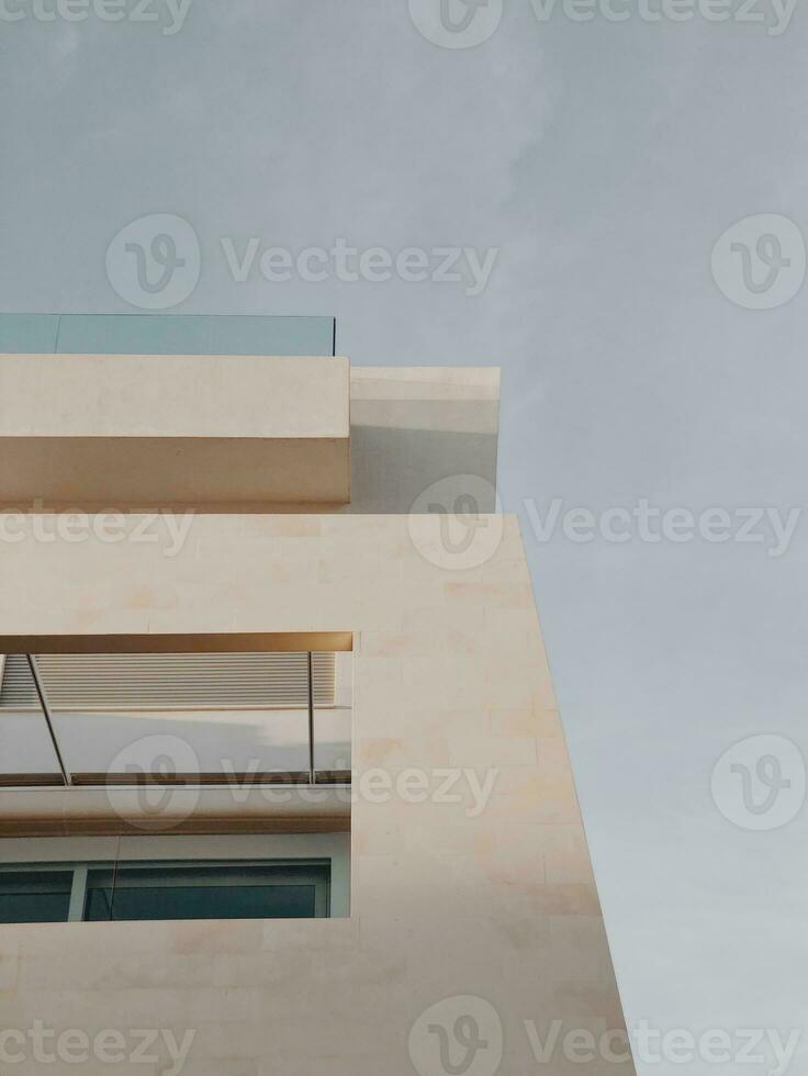 moderno edificio fachada en contra un claro cielo, minimalista arquitectura con geométrico formas y neutral colores. foto