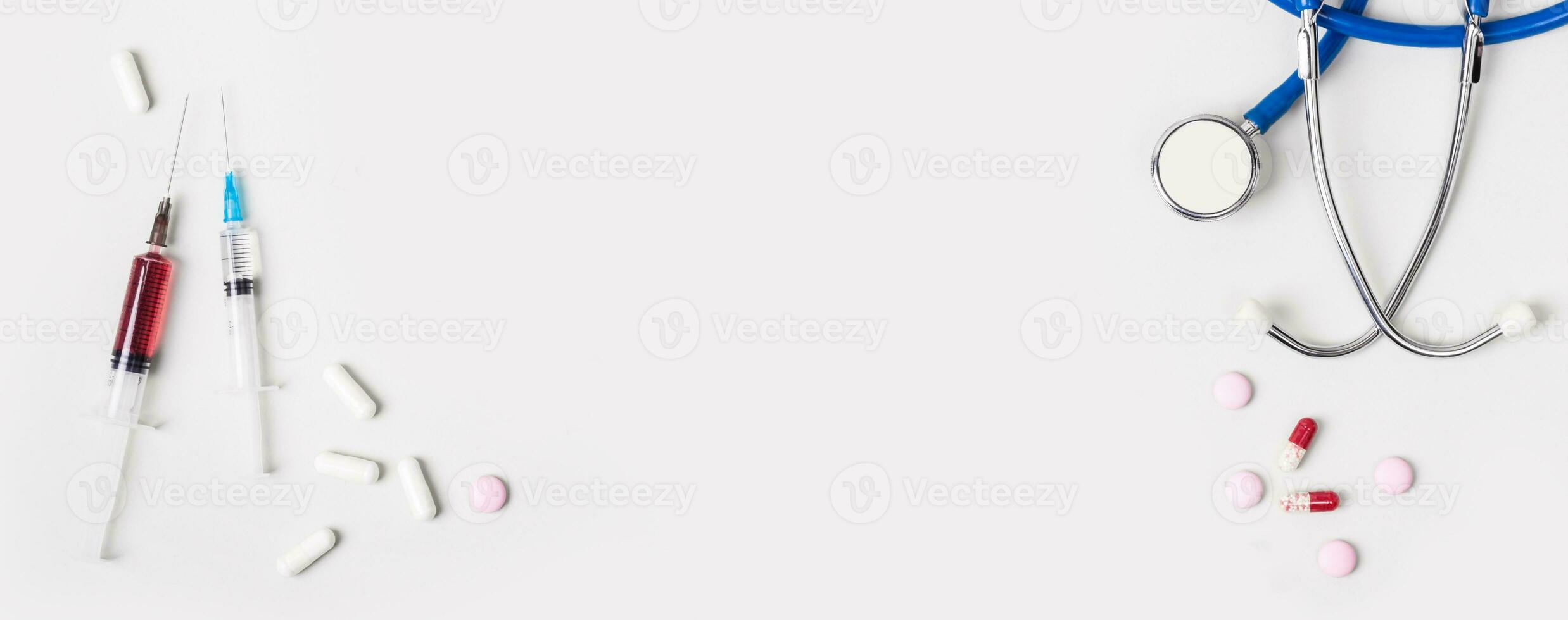 Medicine treatment concept. Various pills, stethoscope and syringes on gray background, banner format photo