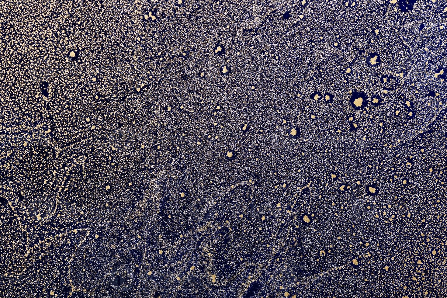 Acrylic Fluid Art. Gold particles pattern on dark blue background. Star dust. Abstract space background or texture photo