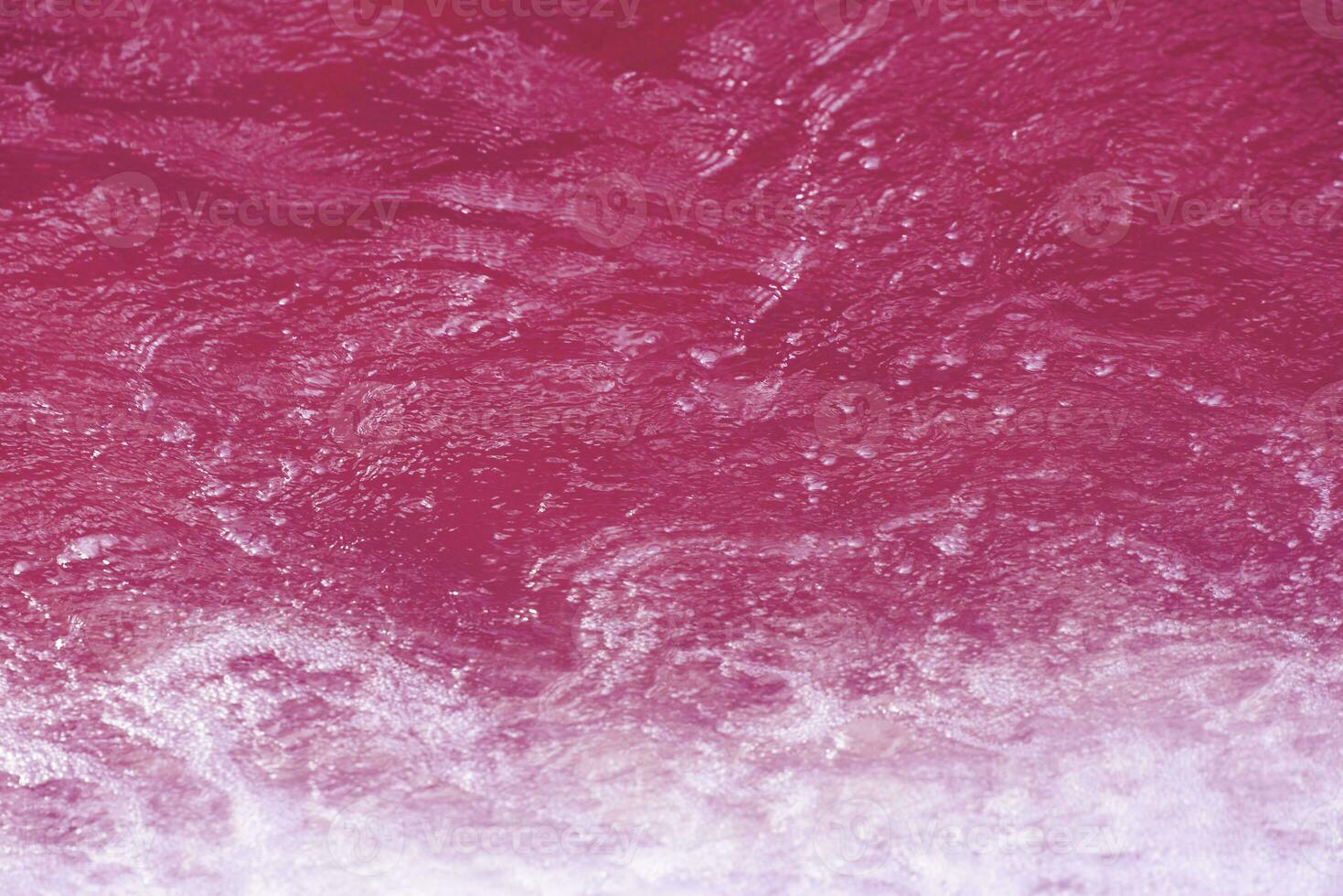 Purple water waves on the surface ripples blur. Defocus blurred transparent pink colored clear calm water surface texture with splash and bubbles. Water waves with shining pattern texture background. photo