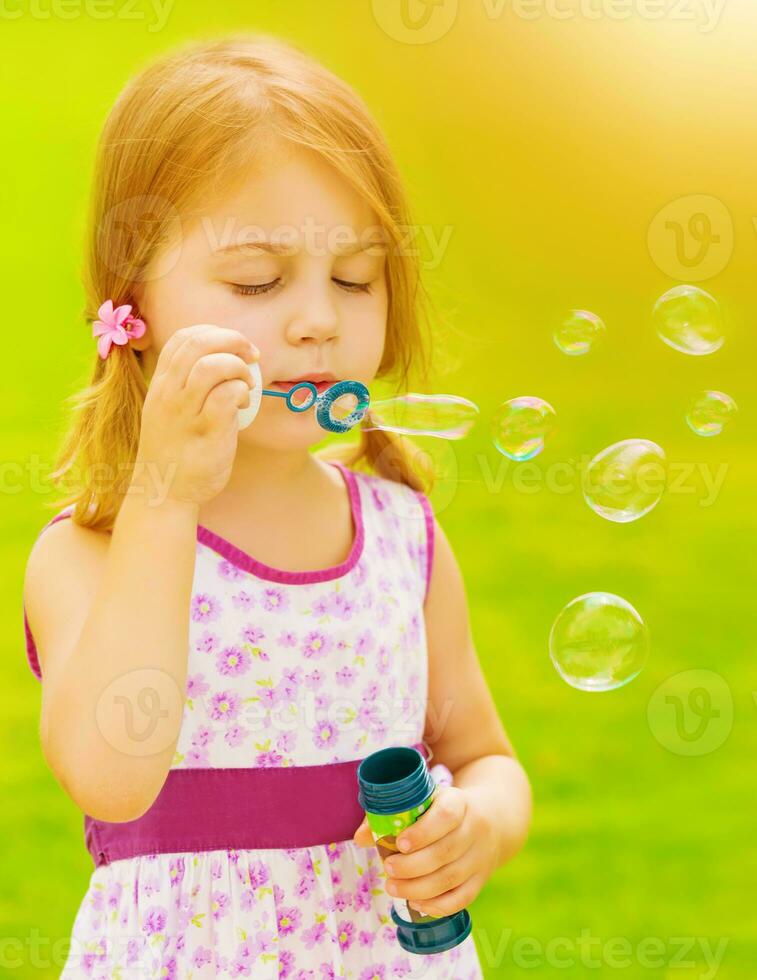 Baby girl blowing soap bubbles photo
