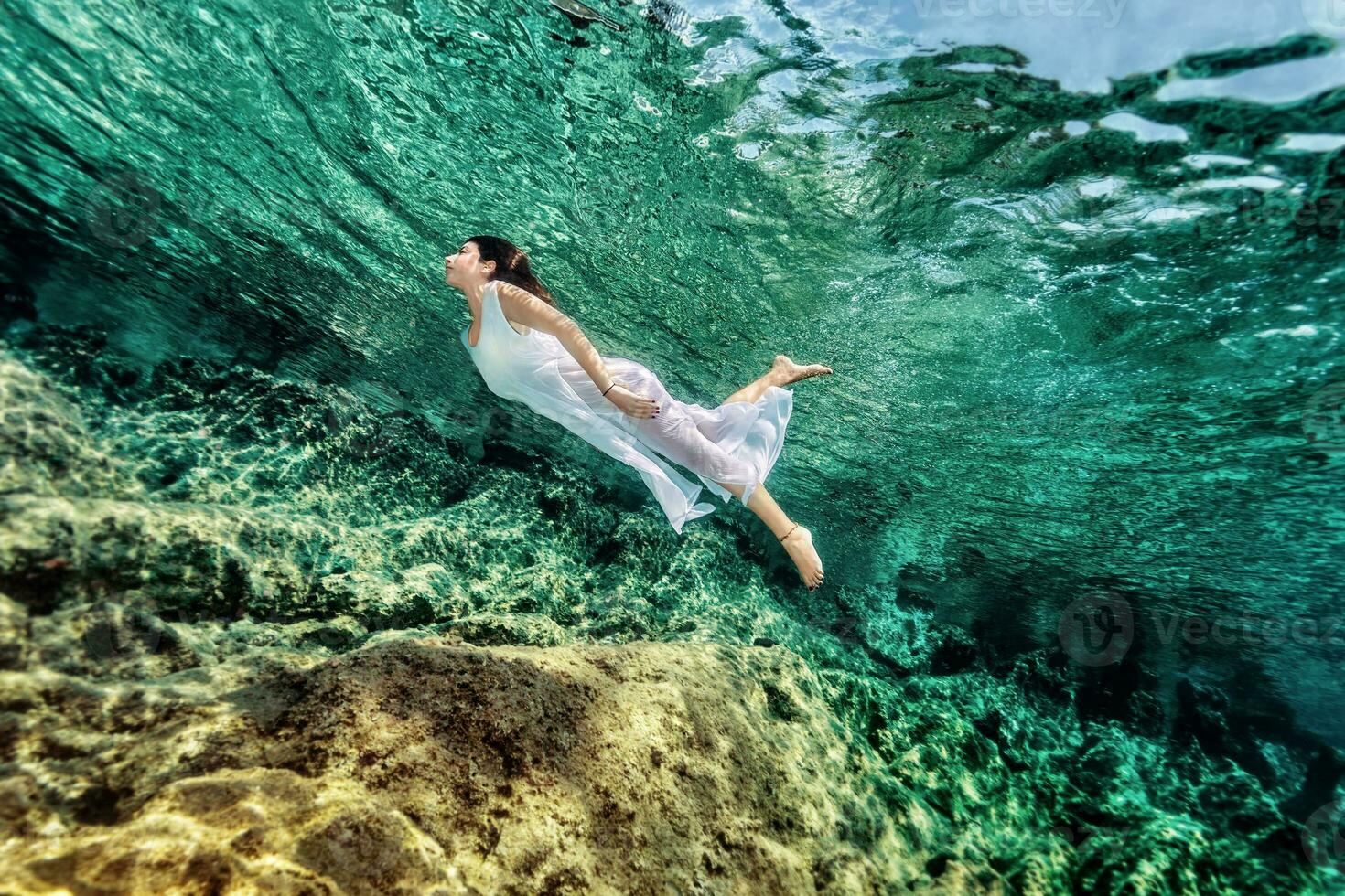 Woman swimming near rock photo