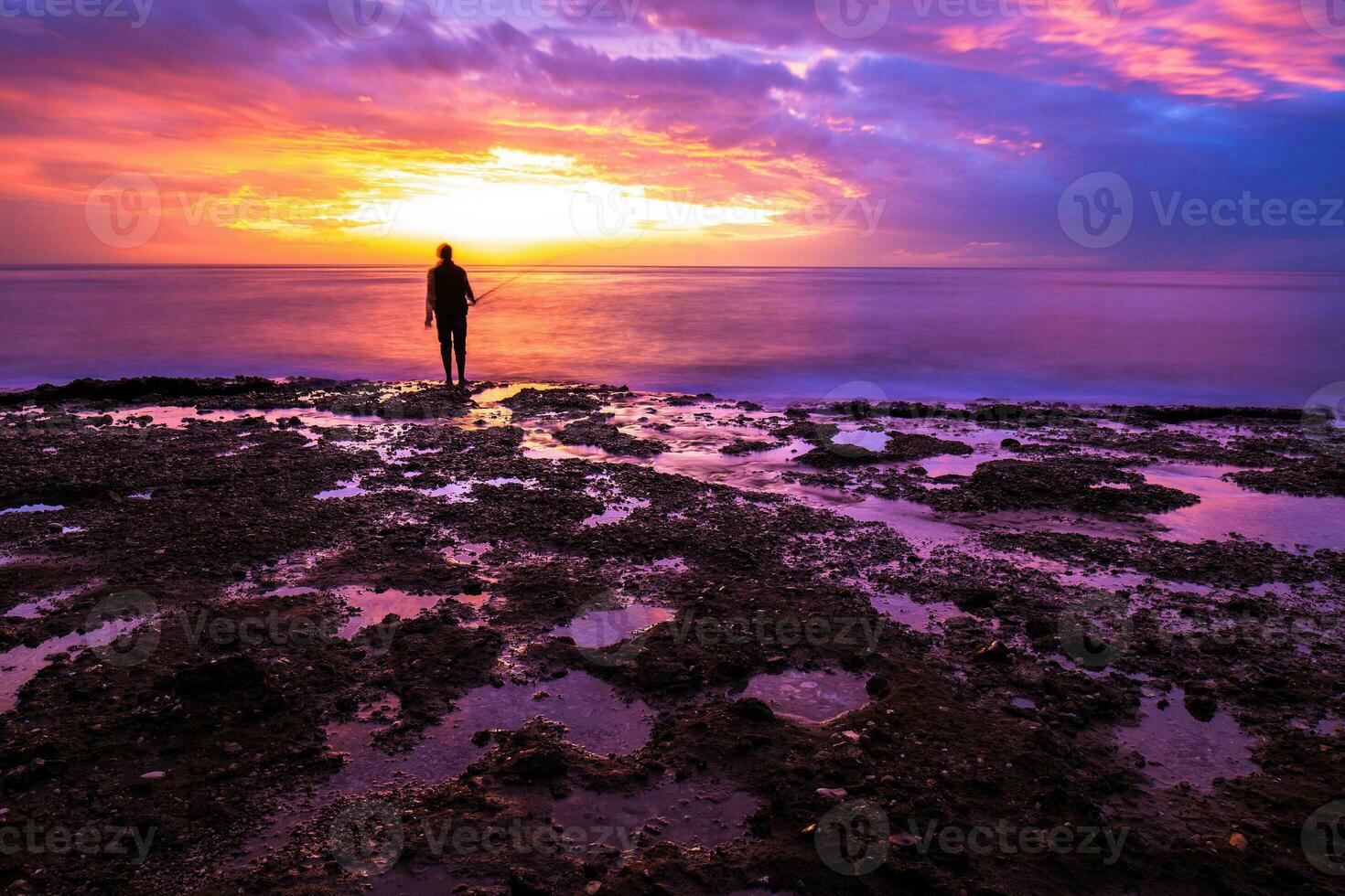 Silhouette of fisherman in sunset photo