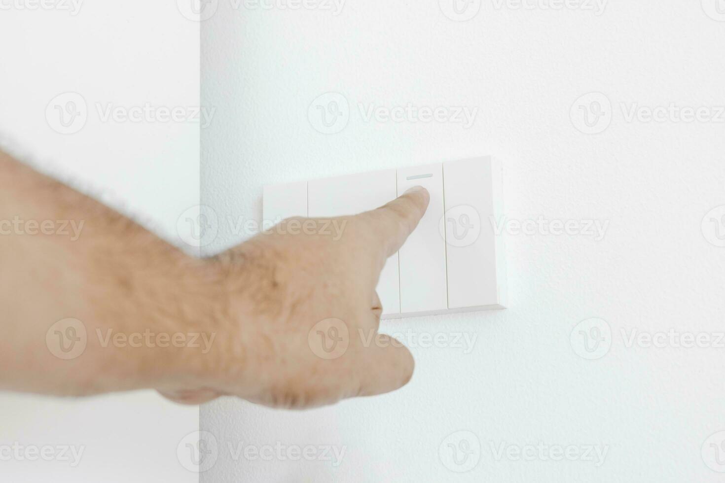 Man uses his finger to turn on a light switch on white wall. Plug studio apartment power supply. Light switch. Power outlet. Concept of technology, connection, power saving, energy saving. photo