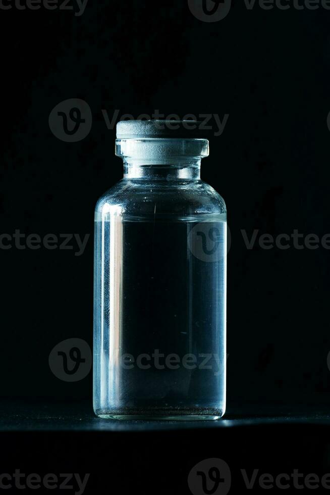 small glass bottle isolated on black photo