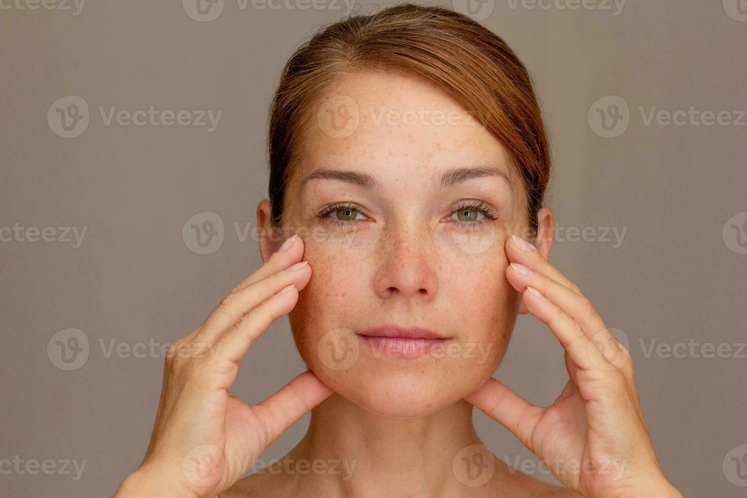 retrato de recortado caucásico medio Envejecido mujer cara con pecas participación dedos en las mejillas foto