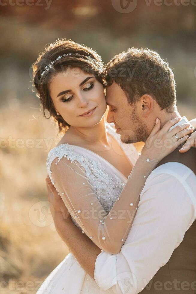 Beautiful wedding couple laughing and kissing against the background of stones. Dress with open shoulders. High quality photo