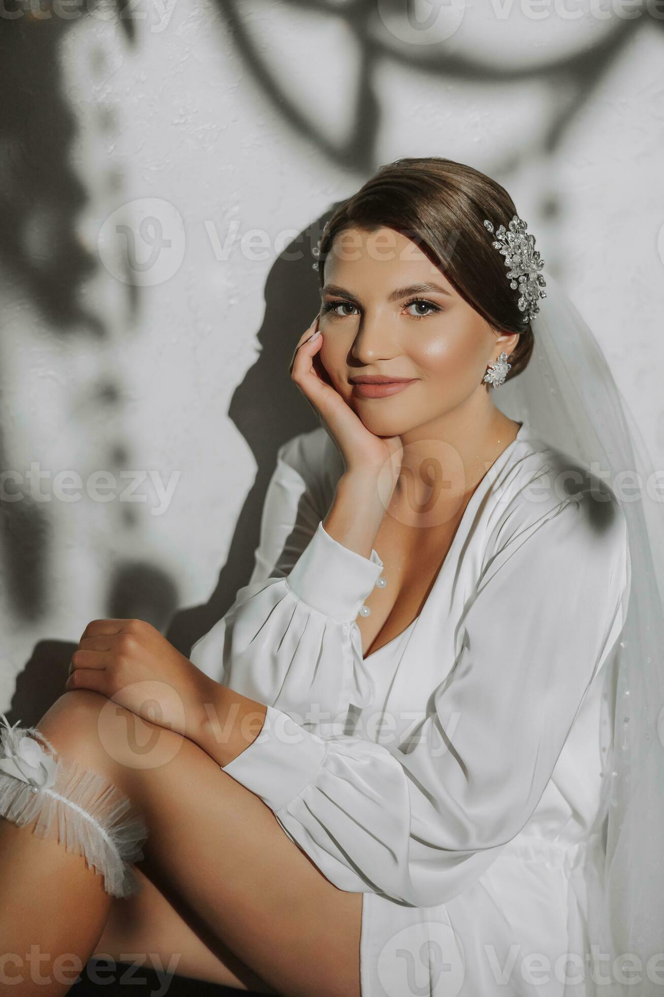 A young bride in a white robe with a wedding garter on her leg, close-up.  Preparation for the wedding ceremony. Accessories for newlyweds, lace garter.  36408880 Stock Photo at Vecteezy