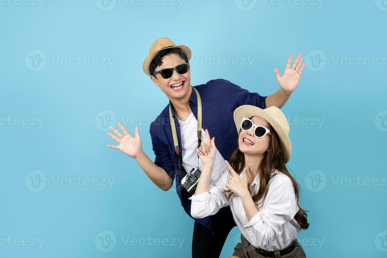 Playful Asian couple wearing casual clothes at the summer beach on a light blue background photo