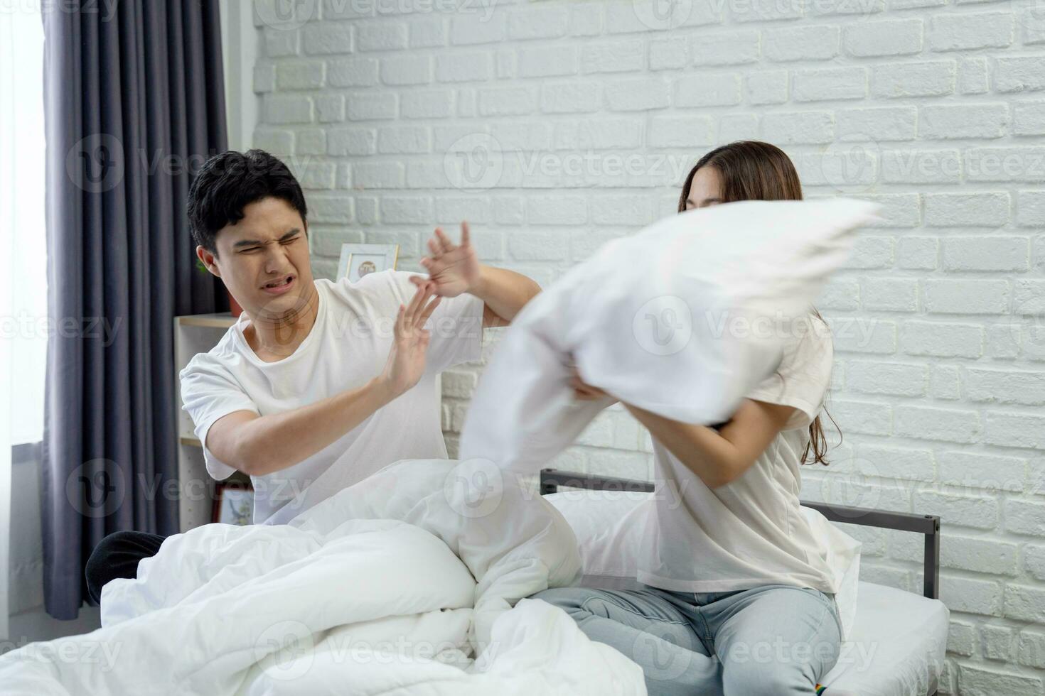 Asian couple in bed arguing on bed at home. They are unhappy and stressed. photo