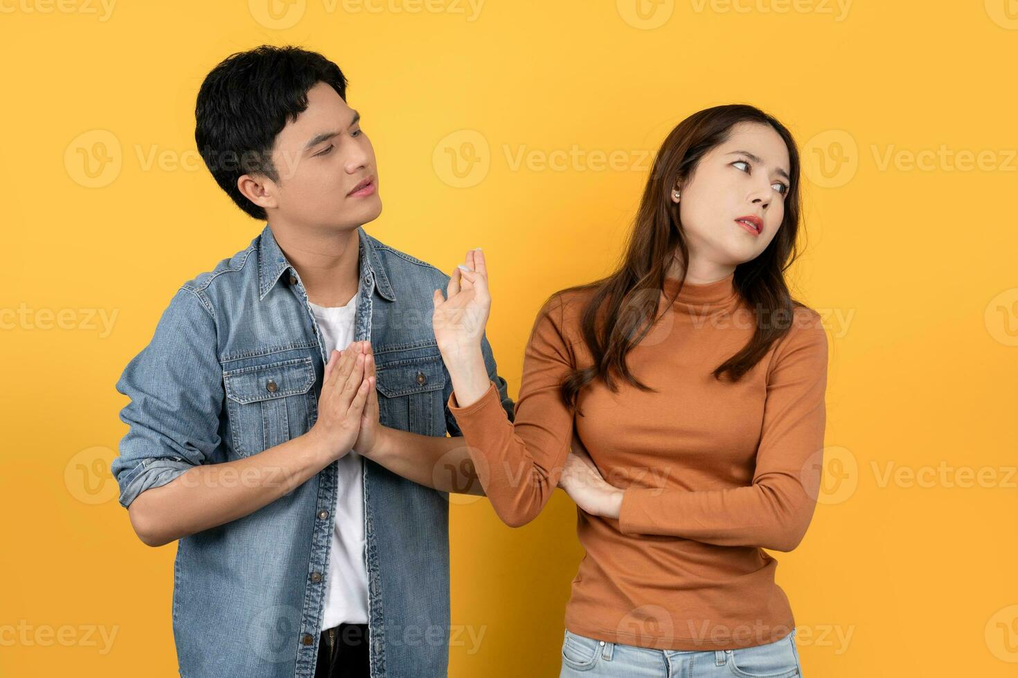 Man and woman quarreling isolated on background. An Asian man is apologizing to his girlfriend. photo