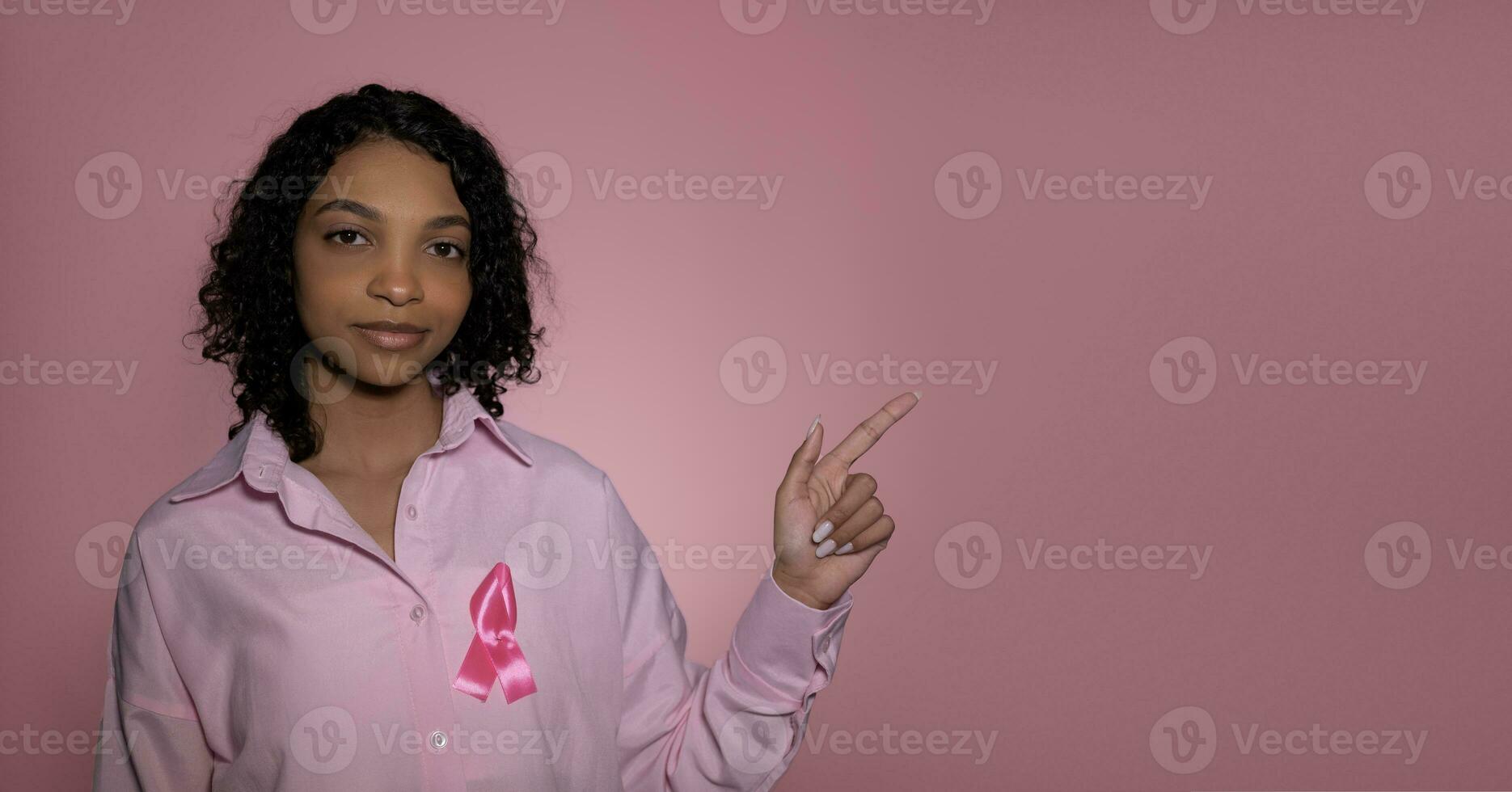 Breast cancer awareness month. banner with girl pointing at empty space. photo