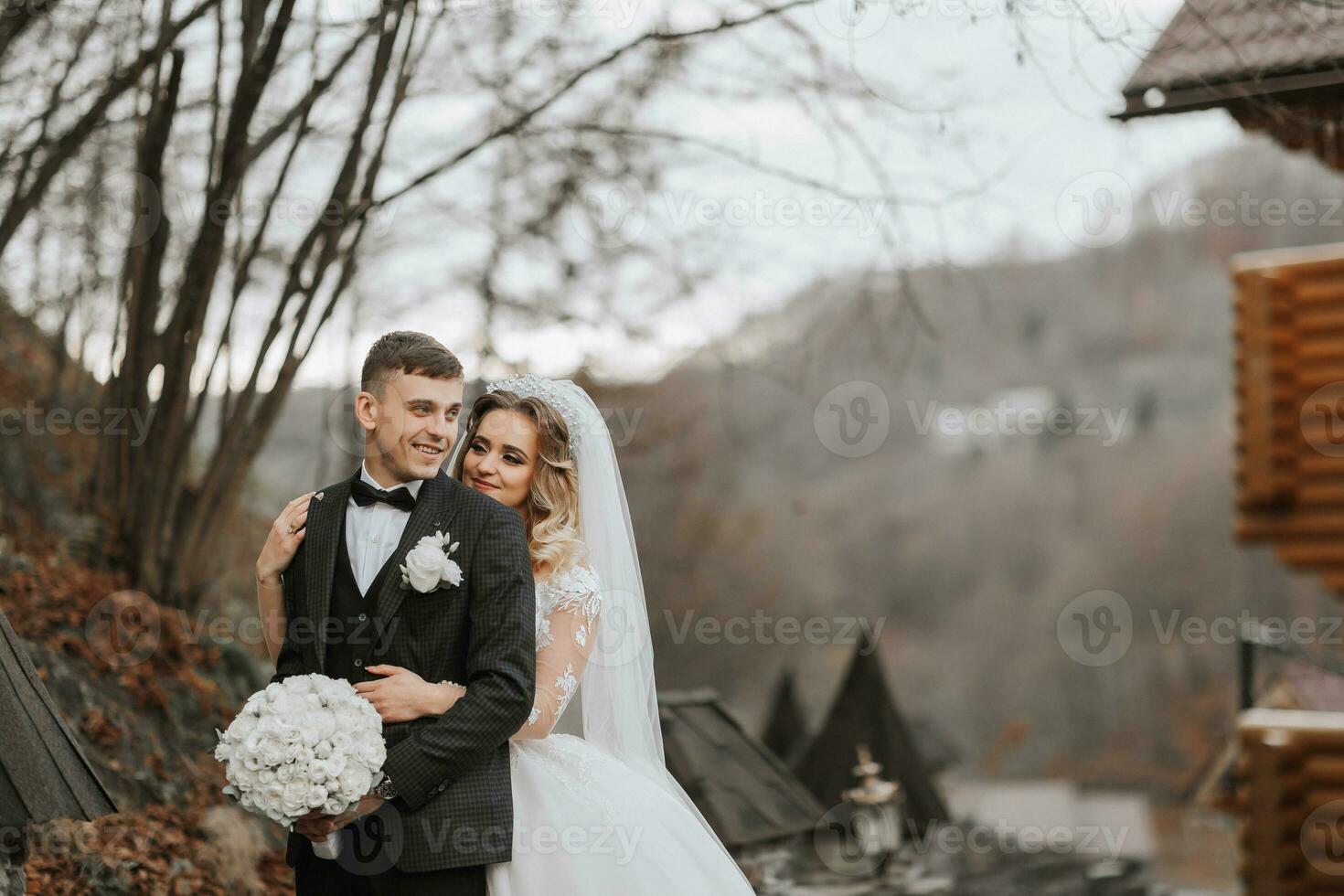 portrait of a young couple of the bride and groom on their wedding day in nature. the bride hugs the groom from behind. stylish portrait. place for copyright photo