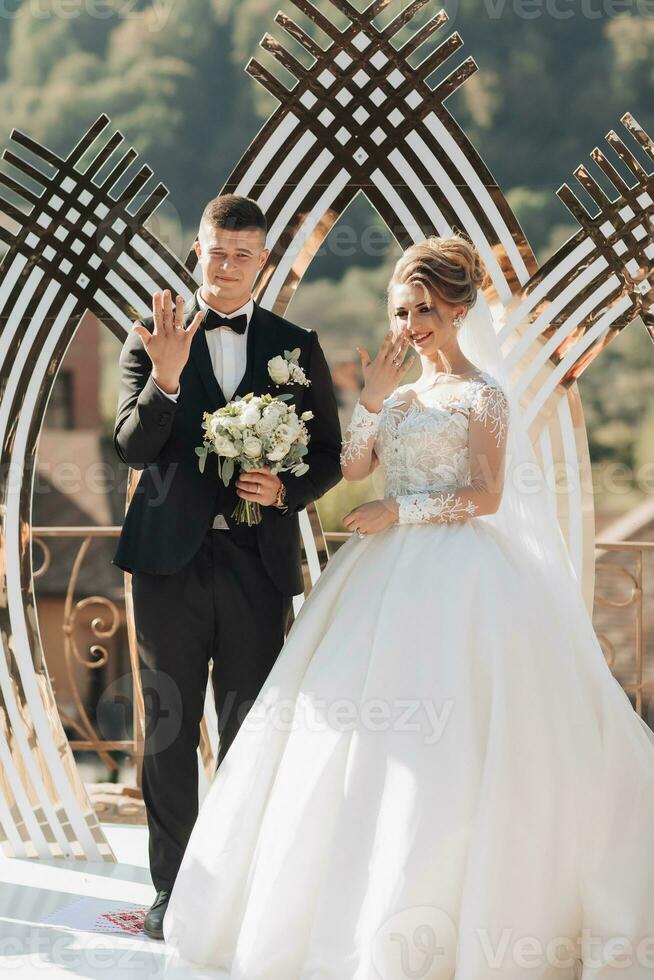 Wedding ceremony painting in nature. Brides and grooms stand by the golden arch during the painting ceremony and show off their engagement rings. An arch in the form of a tulip and fresh flowers photo