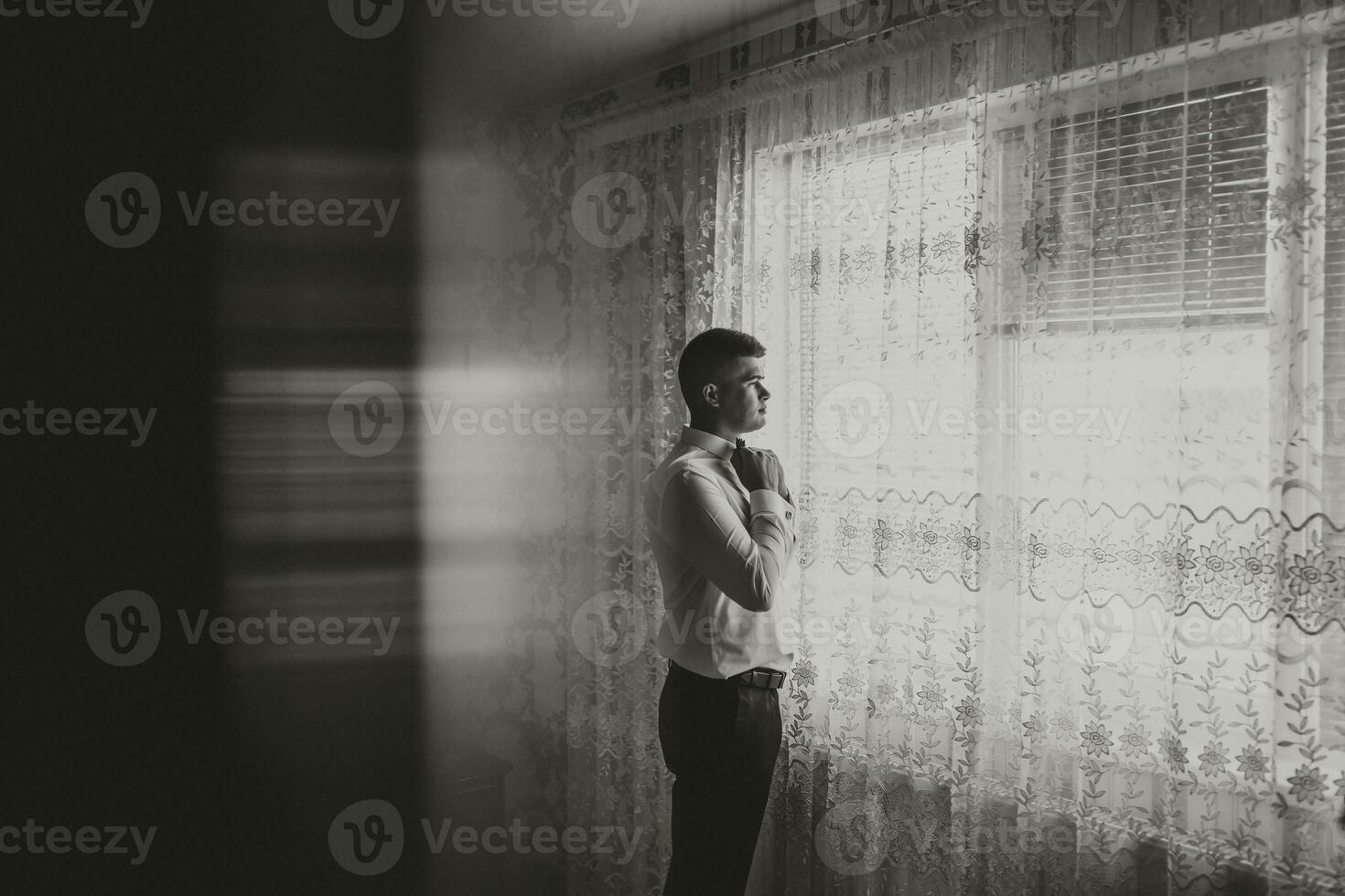 negro y blanco foto. hermoso hombre botones arriba el manga de un blanco camisa y poses para el cámara. frente vista. luz. Moda y estilo. negocio. de los hombres estilo. hermosa manos foto