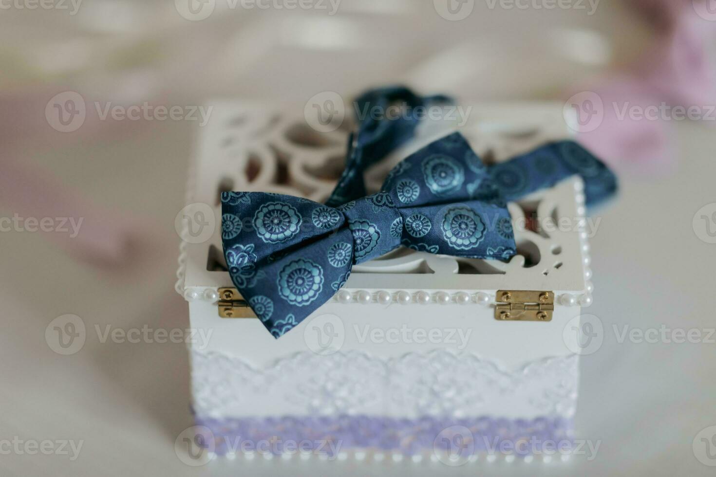 The groom's blue butterfly is standing on a wooden box with wedding rings on a white background. Wedding details. Style. photo