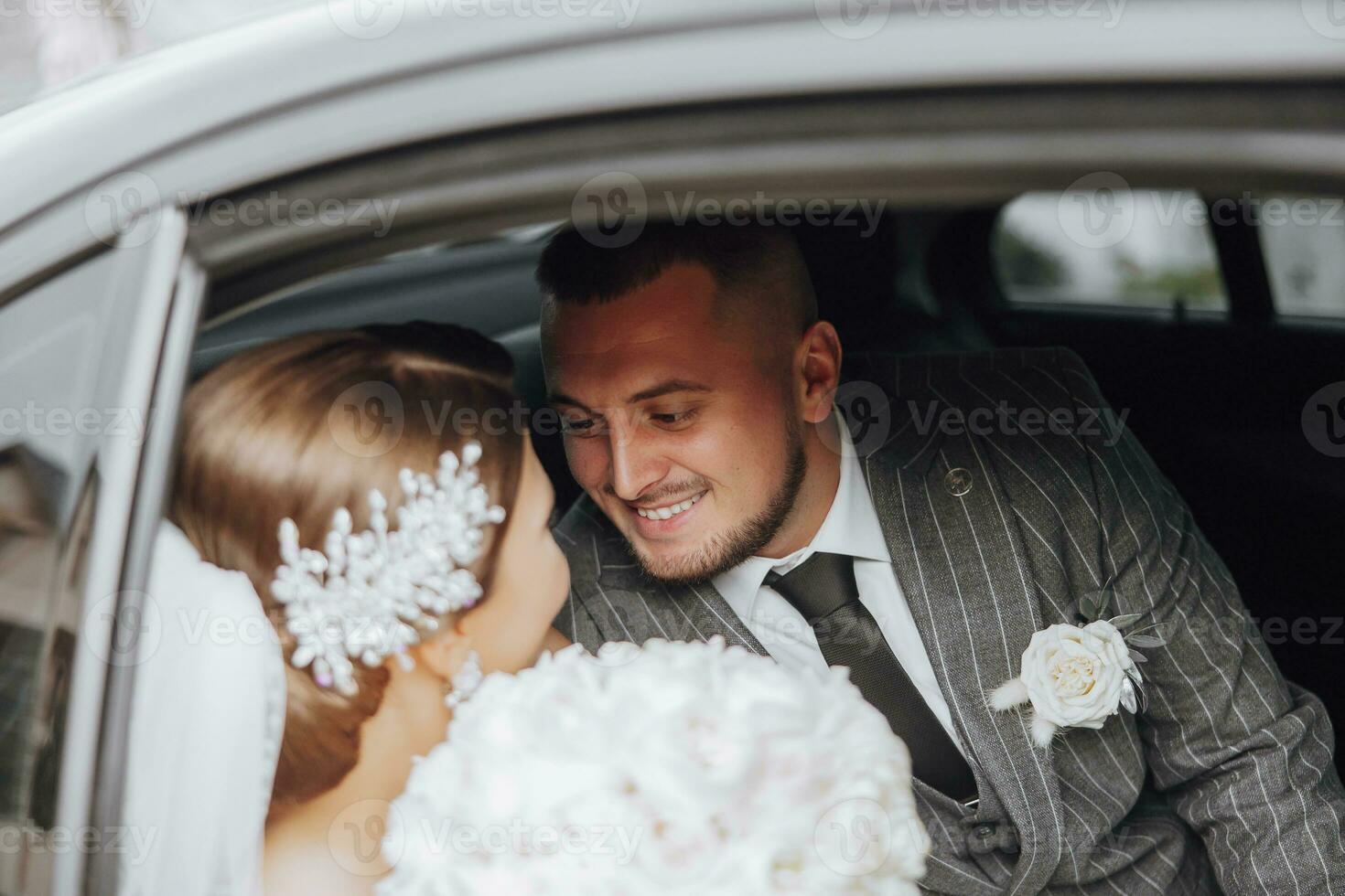 A modern bride and groom in a lace dress in a car window. Beautiful and smiling newlyweds. Happy holiday. photo