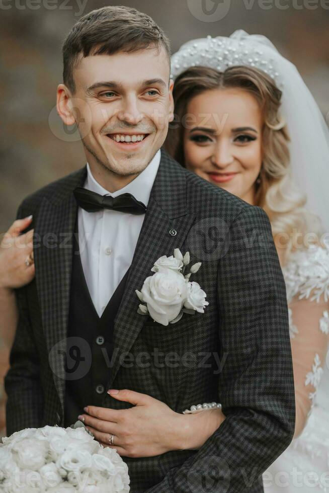 portrait of a young couple of the bride and groom on their wedding day. the bride hugs the groom from behind. stylish portrait close-up photo