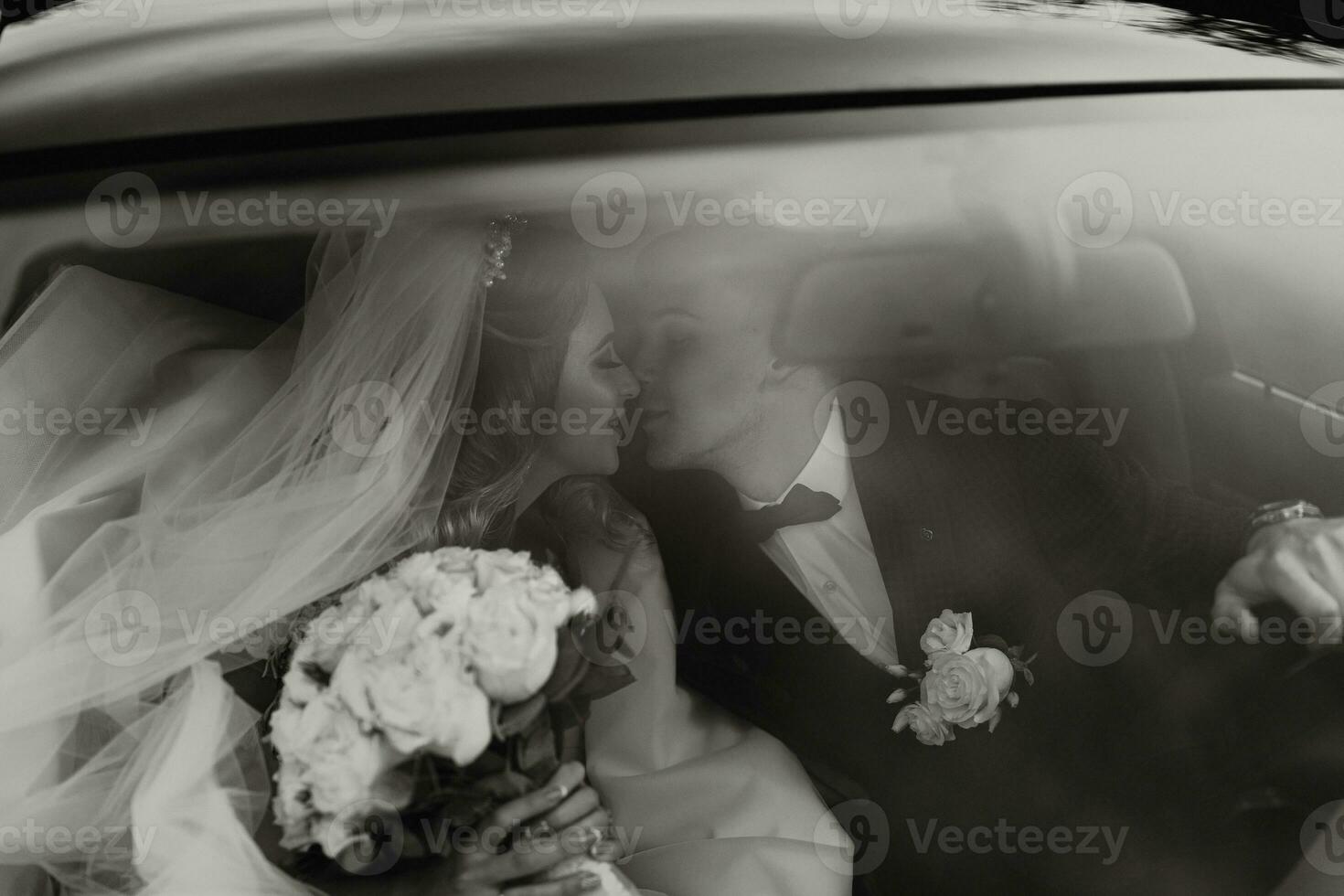 luxury elegant wedding couple embracing in stylish black car in light. gorgeous bride and handsome groom in retro style. black white photo