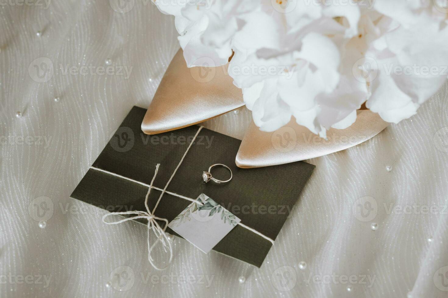 wedding accessories in light colors, shoes, a wedding ring and a wedding bouquet. Invitation from embossed paper in green color photo