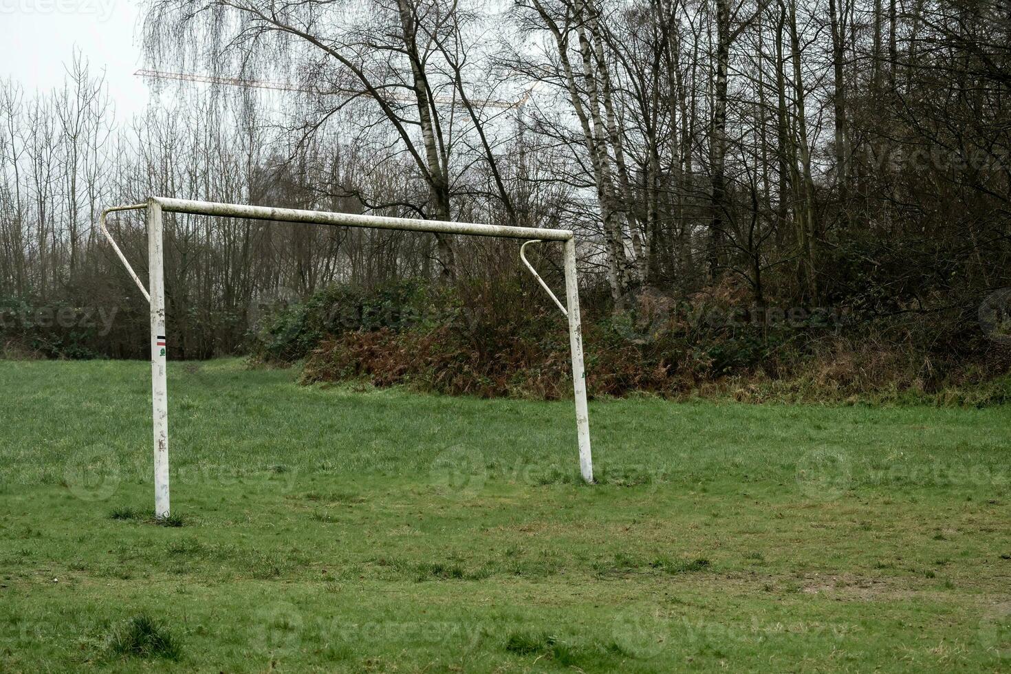 poorly maintained soccer pitch with old soccer goal in the rain photo
