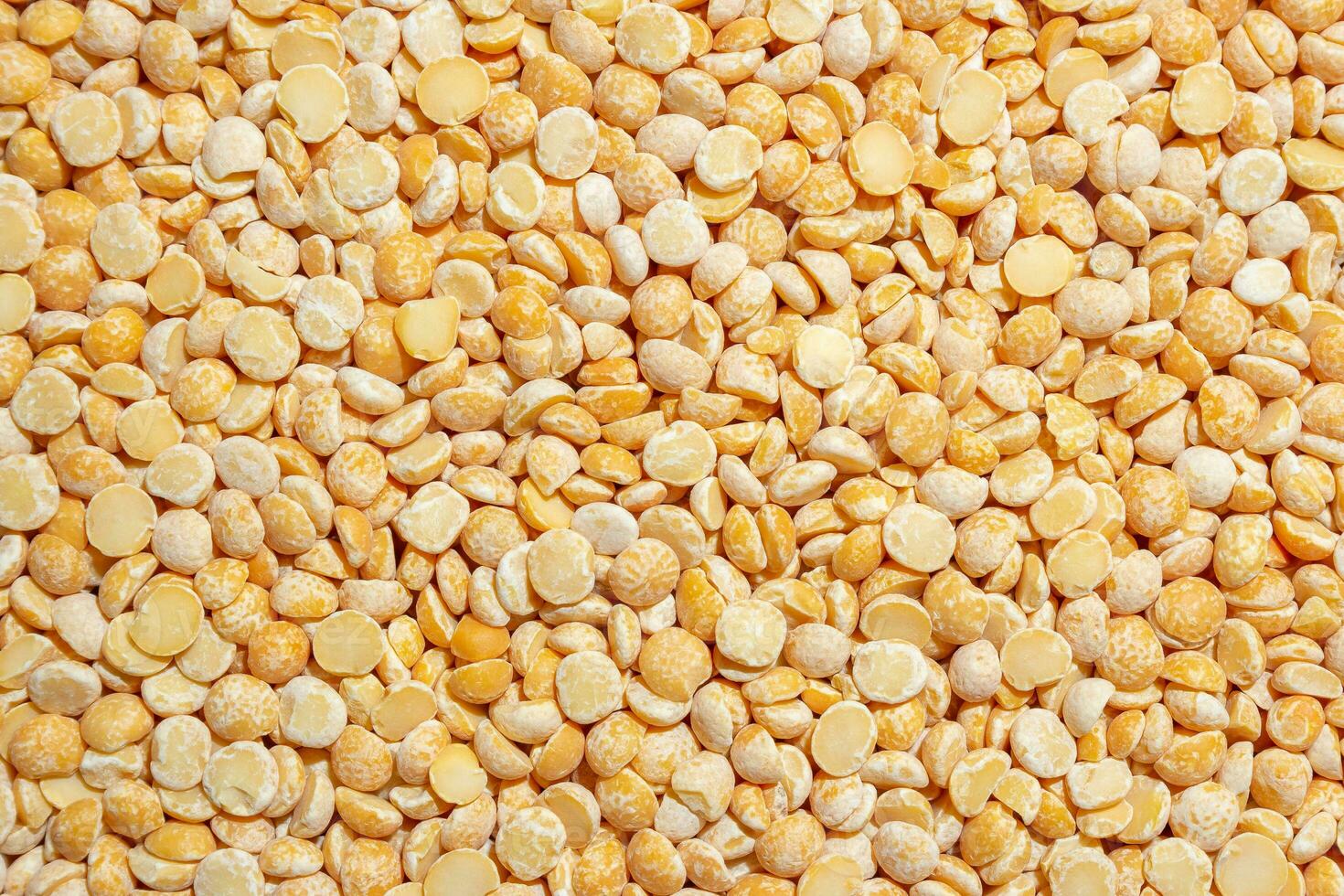 Uncooked Polished Split Peas Background. A Culinary Canvas of Dry Yellow Peas, Creating a Lively and Textured Background for Gourmet Cooking. Scattered Raw Polished Peas. Healthy Eating Ingredients photo