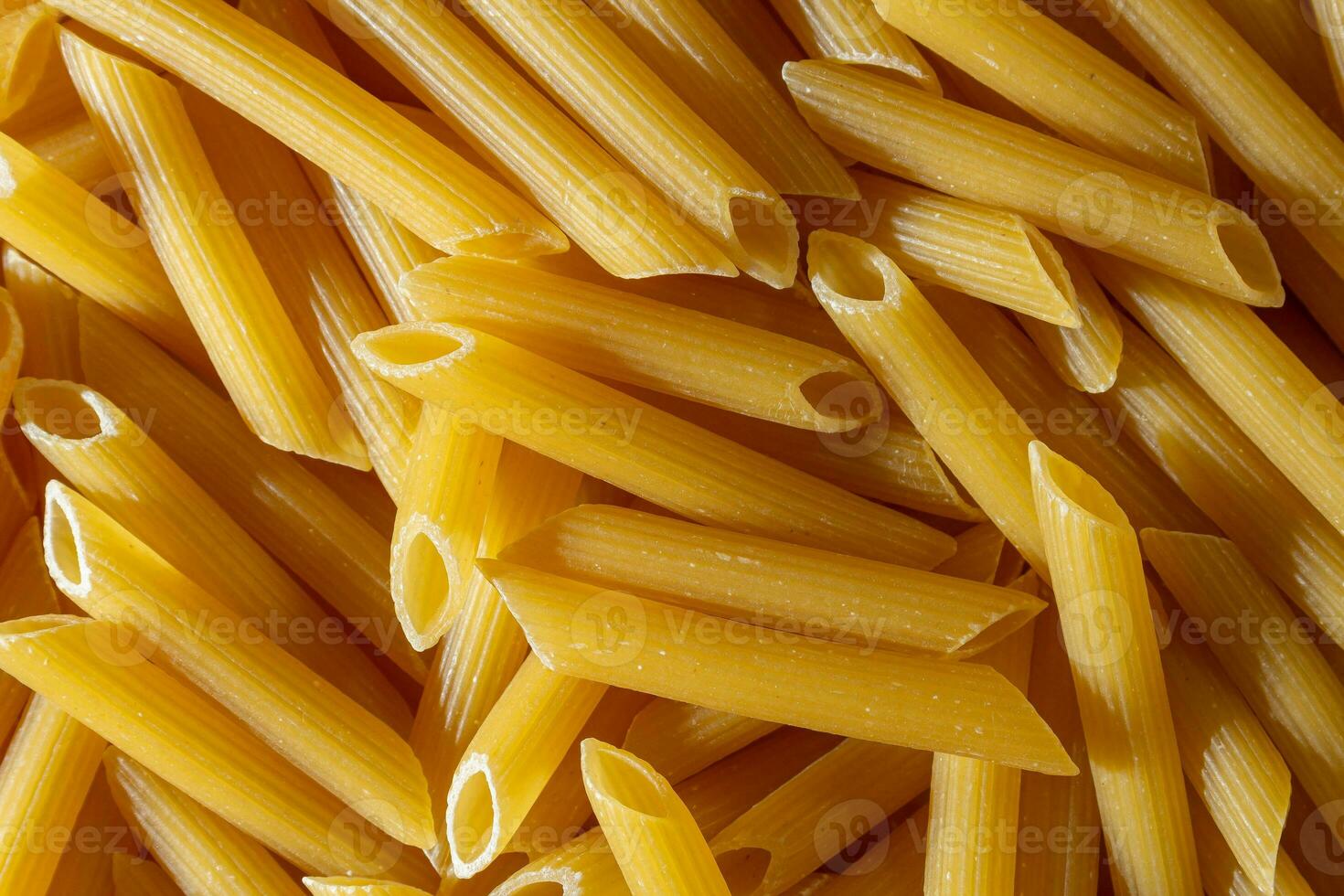 Uncooked Penne Rigate Pasta. A Culinary Canvas of Penne Macaroni, Creating a Lively and Textured Background for Gourmet Cooking. Dry Pasta. Raw Macaroni - Top View, Flat Lay photo