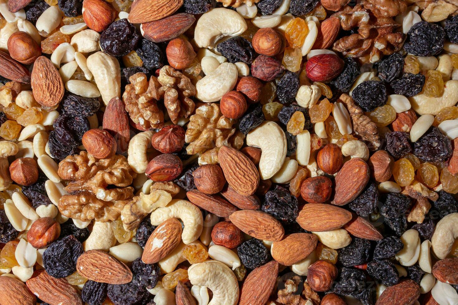 Mixed Nuts. Almonds, Walnuts, Cashews, Peanuts, Hazelnuts, Dried Prunes and Raisins. Different Nut Mix. Background from Various Nuts and Dried Fruits photo